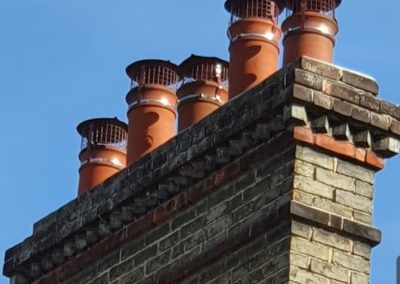 Brick chimney stack with multiple terracotta chimney pots