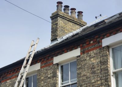 Brick chimney stack with capped clay chimney pots on a slate roof