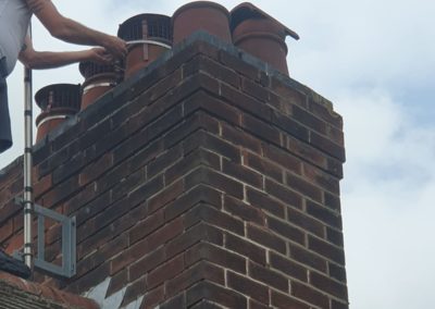 Roofer installing chimney caps on a brick chimney