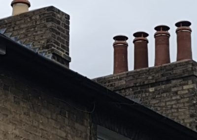 Brick chimney with multiple chimney pots on a tiled roof