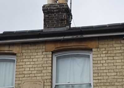 Brick chimney with chimney pots and a television aerial on a slate roof
