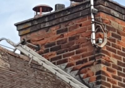 Brick chimney with metal aerial and chimney cowls | Cambridge Roofing Repairs