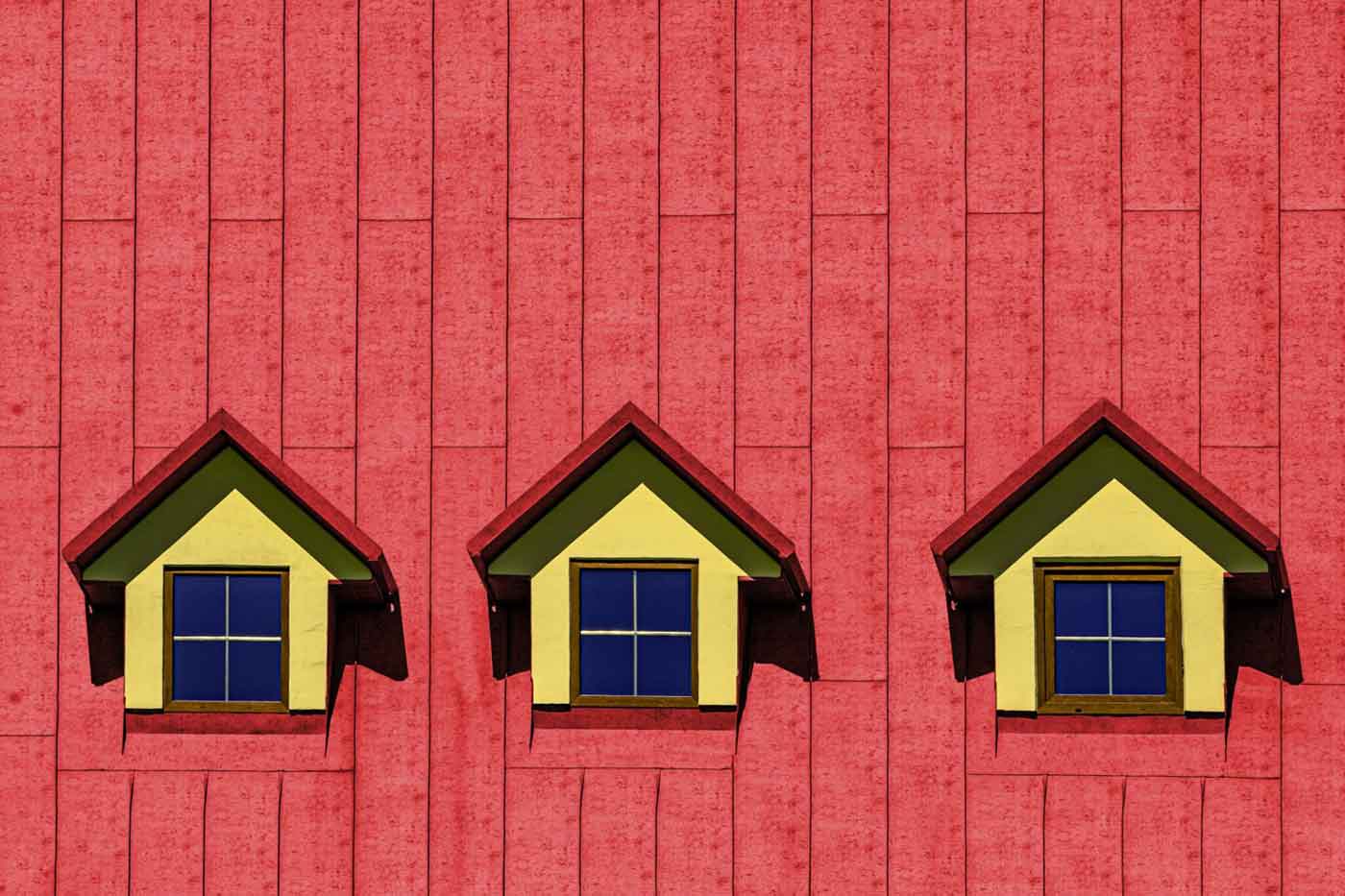 Red roof with three small dormer windows and yellow trim